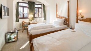 A hotel room with two beds, a desk, a chair, a television, and a minibar. - Hotel Deutscher Kaiser (Nuremberg)