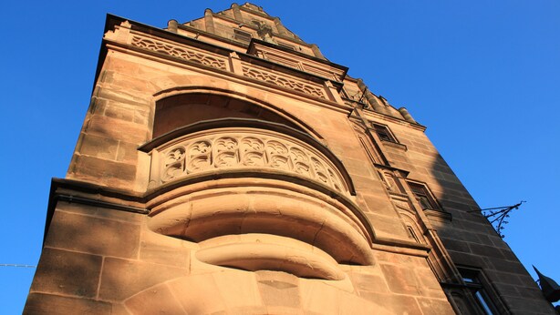 A stone tower with intricate carvings and a clock. - Hotel Deutscher Kaiser (Nuremberg)