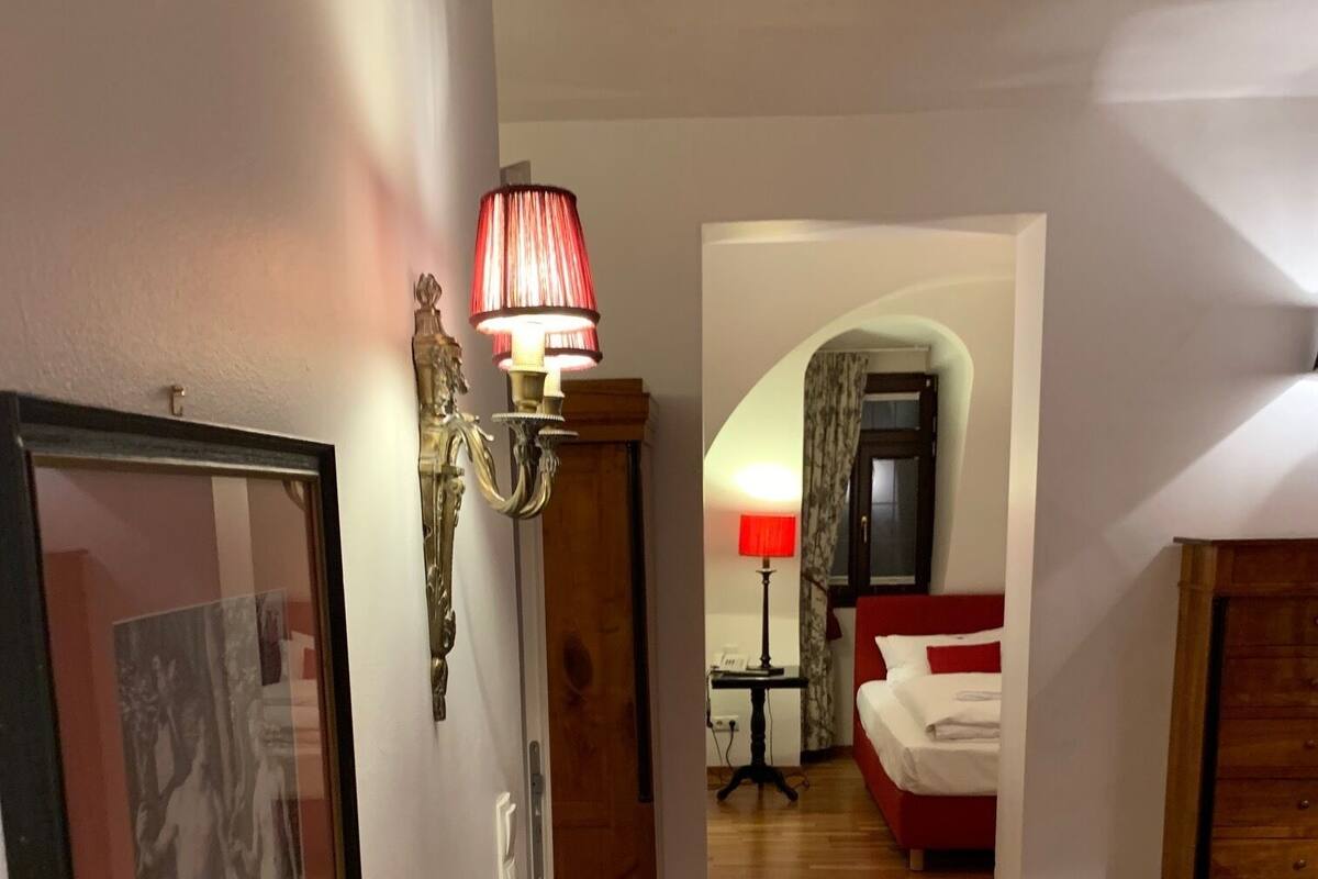 Una habitación con un sofá blanco, un cuadro en la pared, una lámpara y un aparador de madera.