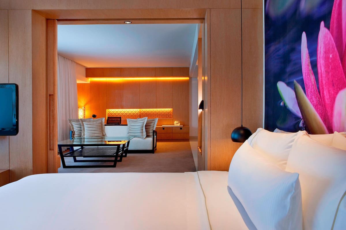 A hotel room with a bed, a seating area with a table and chairs, and a wall-mounted TV.