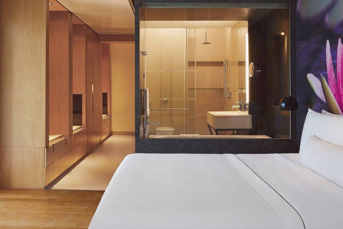 A hotel room with a large bed, a TV, and a view of the city through a window.