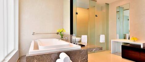 A modern bathroom with a large bathtub, a marble countertop, and a glass shower enclosure.