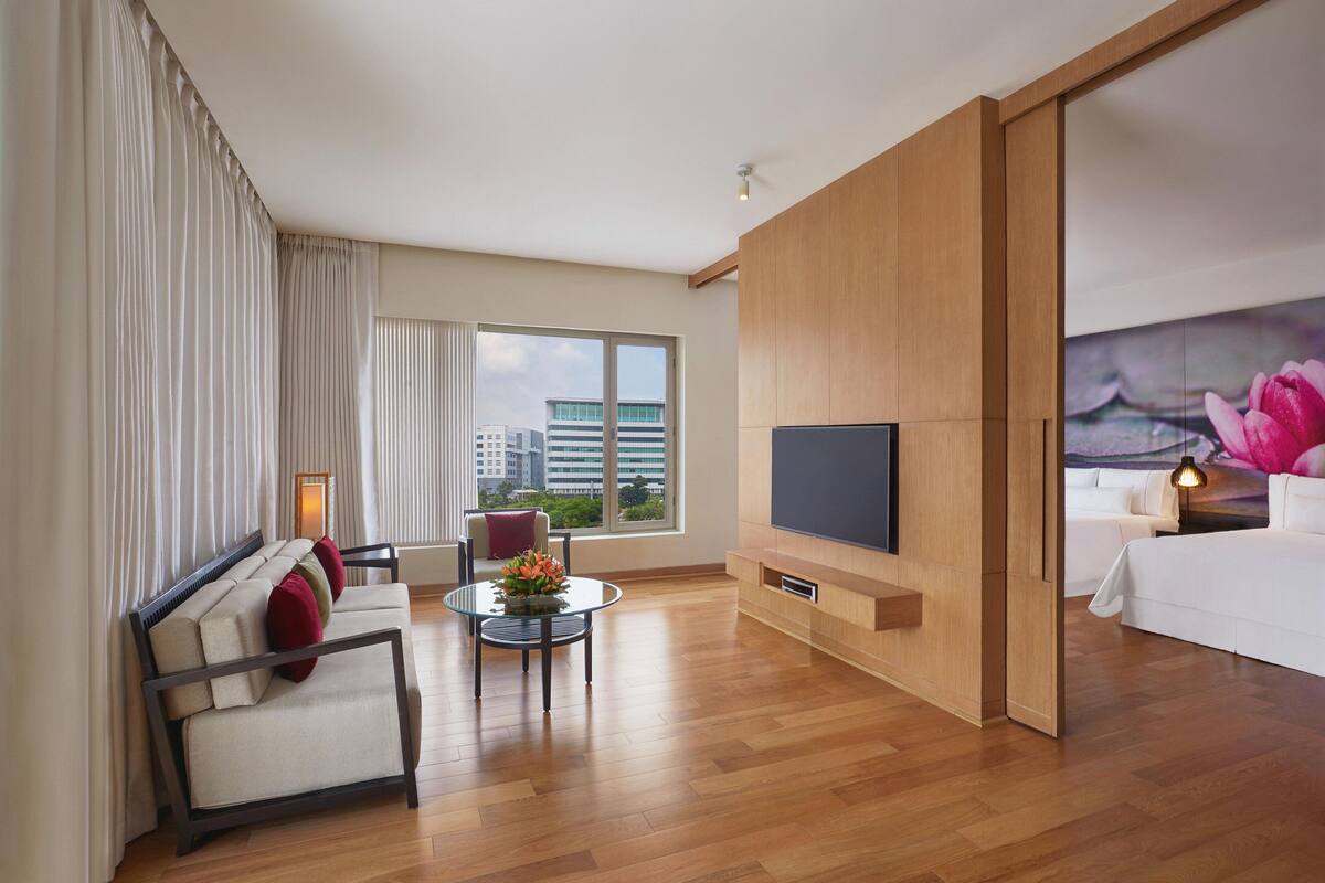 A modern hotel room with a sofa, a small table, a TV, and a bed.