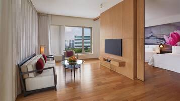 A modern hotel room with a sofa, a small table, a TV, and a bed.
