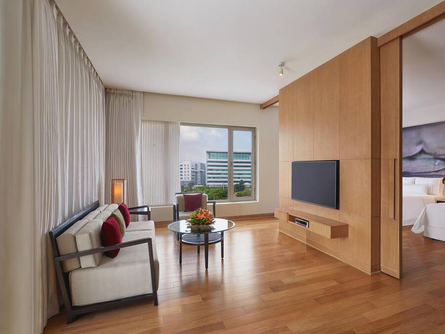 A modern hotel room with a sofa, a small table, a TV, and a bed.