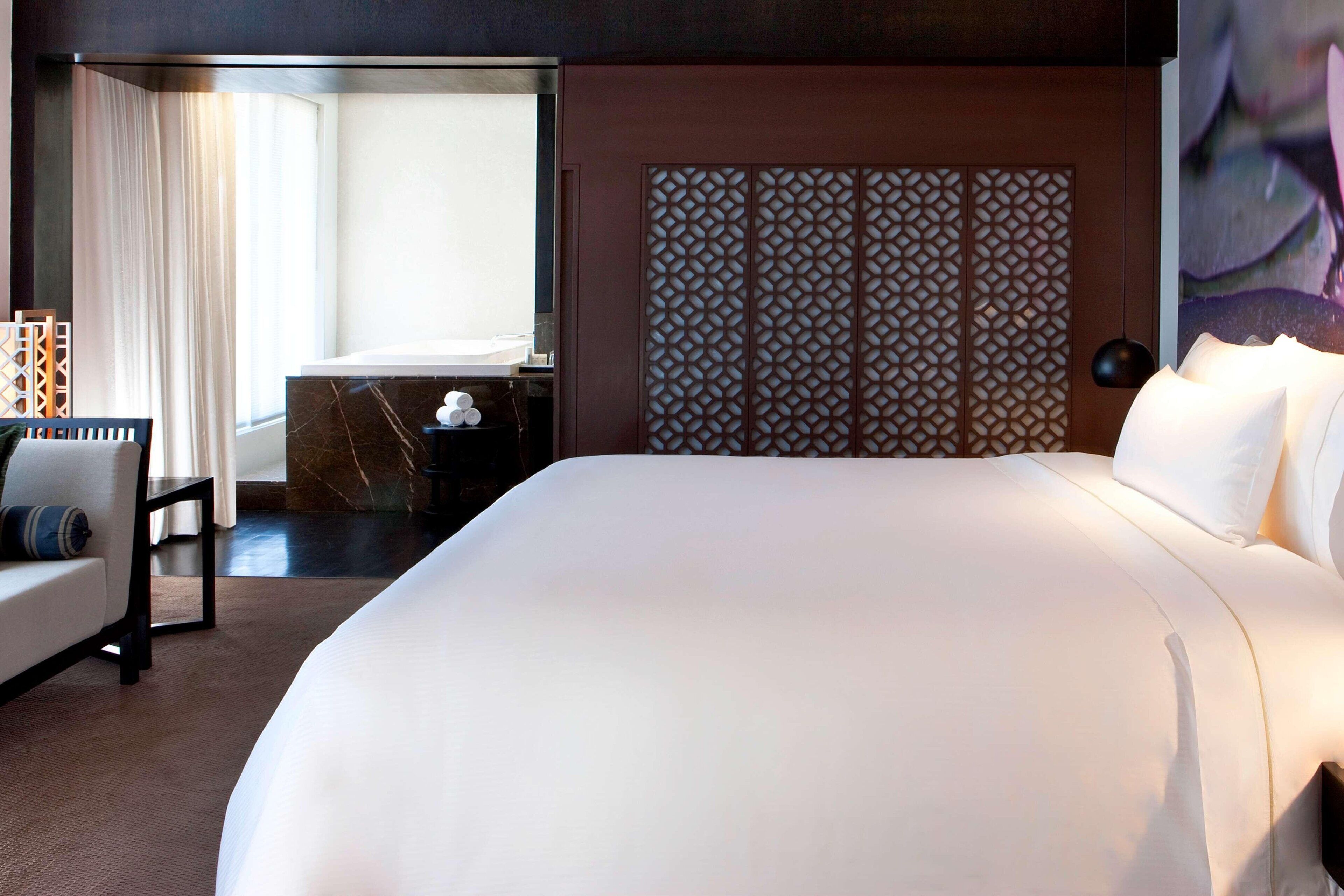 Una habitación de hotel con una cama grande, un escritorio, una silla y un biombo decorativo.