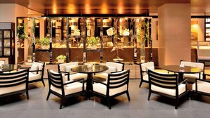 Un intérieur moderne avec un espace salon comprenant des tables et des chaises rondes, un mur décoratif avec des étagères et divers objets exposés.