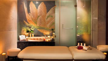 Experience serenity in this spa room, featuring a massage table, glass-enclosed shower, and calming ambiance.