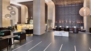 Un hall d’entrée moderne doté d’espaces aménagés avec des sièges, d’un comptoir de réception et d’un mur décoratif.