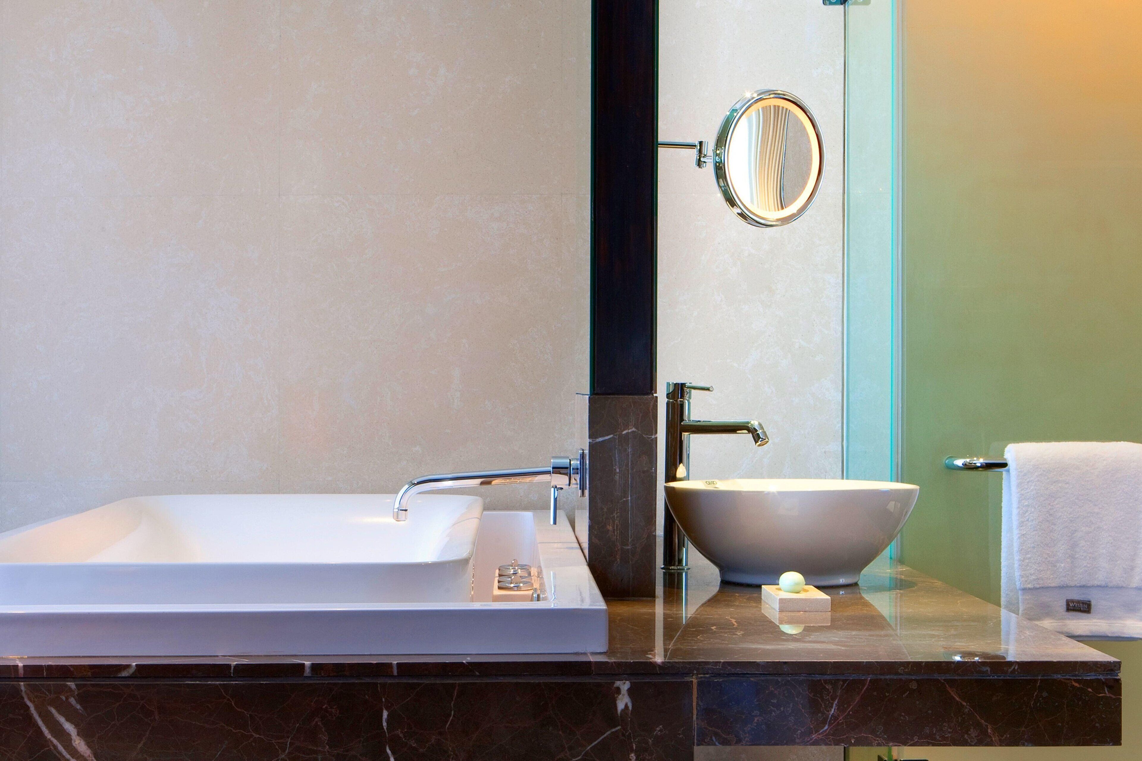 A bathroom with a large rectangular sink, a vessel sink, a mirror, and a towel rack.