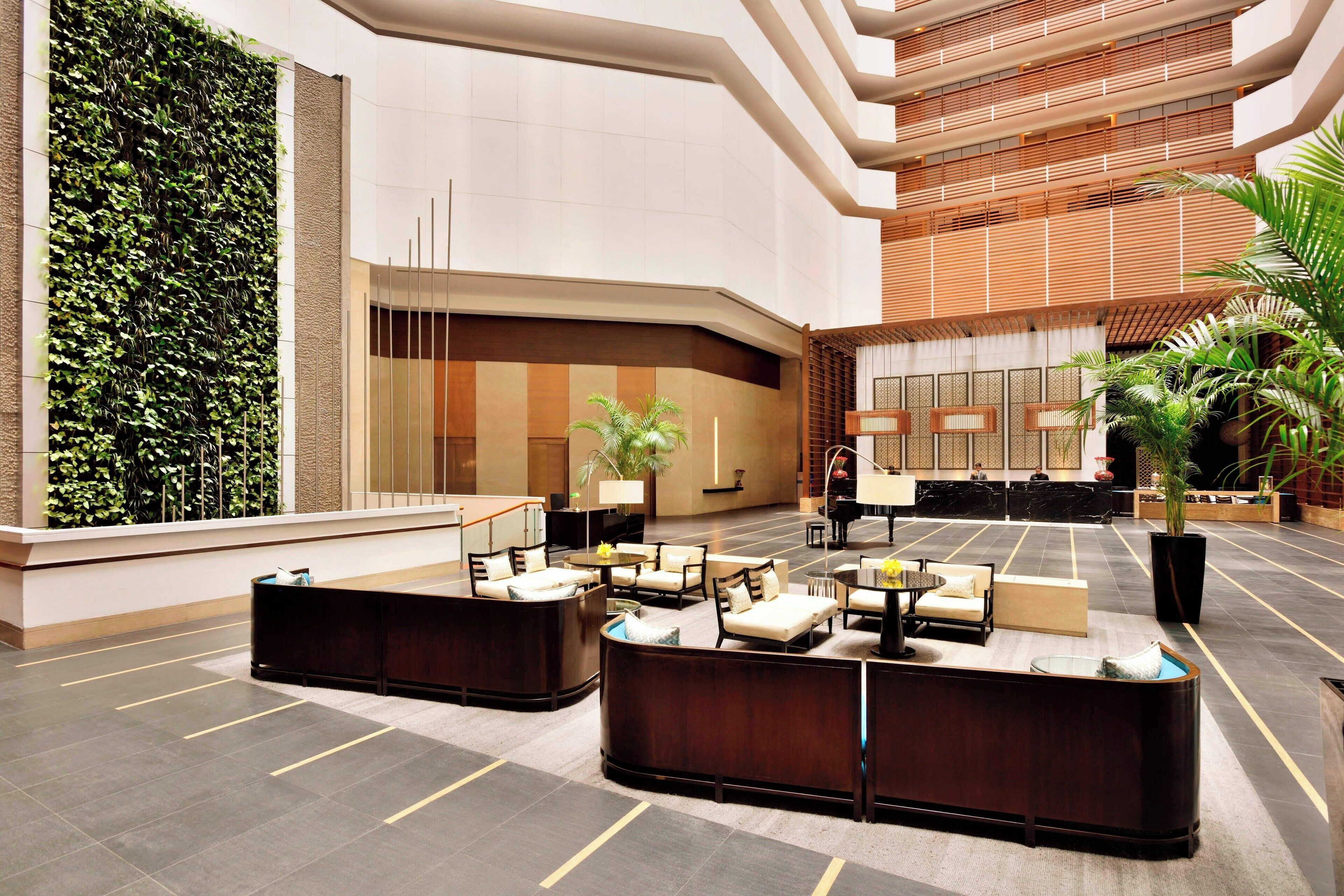 A modern lobby with a reception desk, seating area, and a vertical garden.