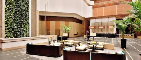 A modern lobby with a reception desk, seating area, and a vertical garden.
