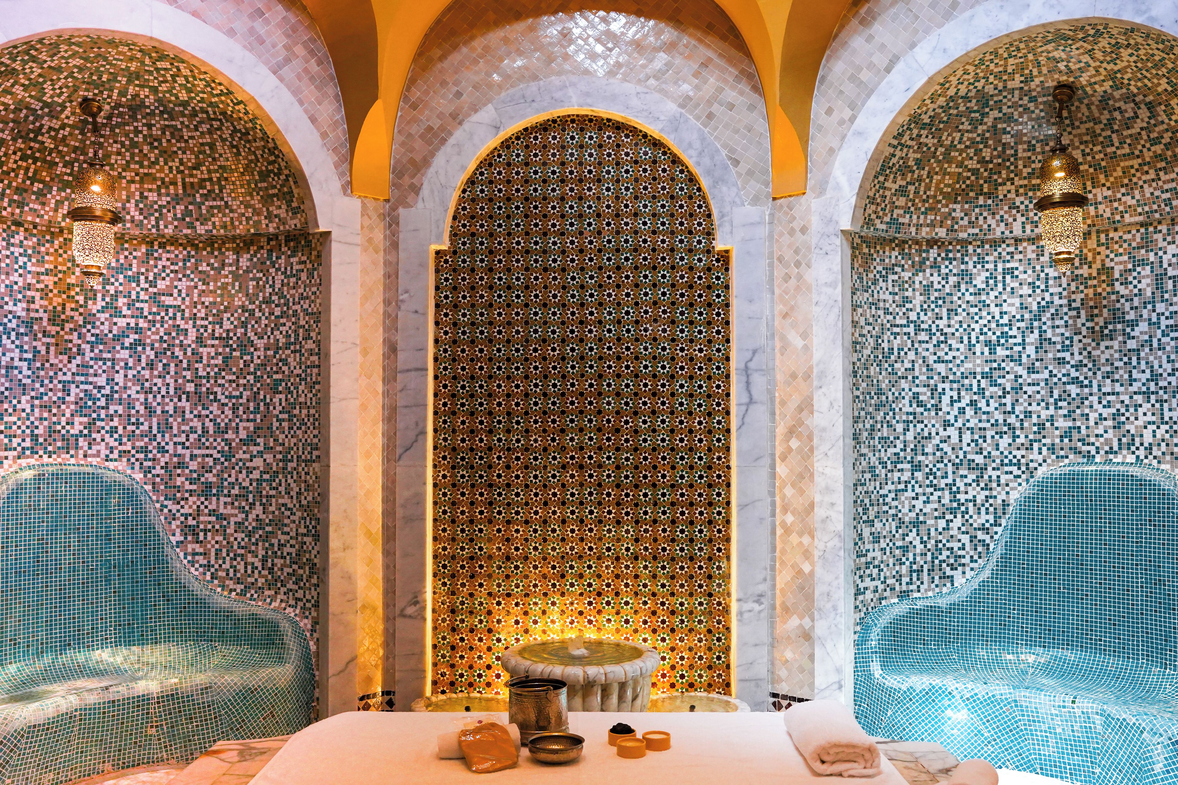 A luxurious spa area with mosaic-tiled walls, a central fountain, and seating areas.
