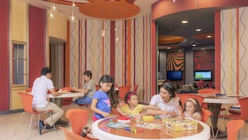 Children can play and relax in this vibrant space with a central table, colorful walls, and a TV for entertainment.
