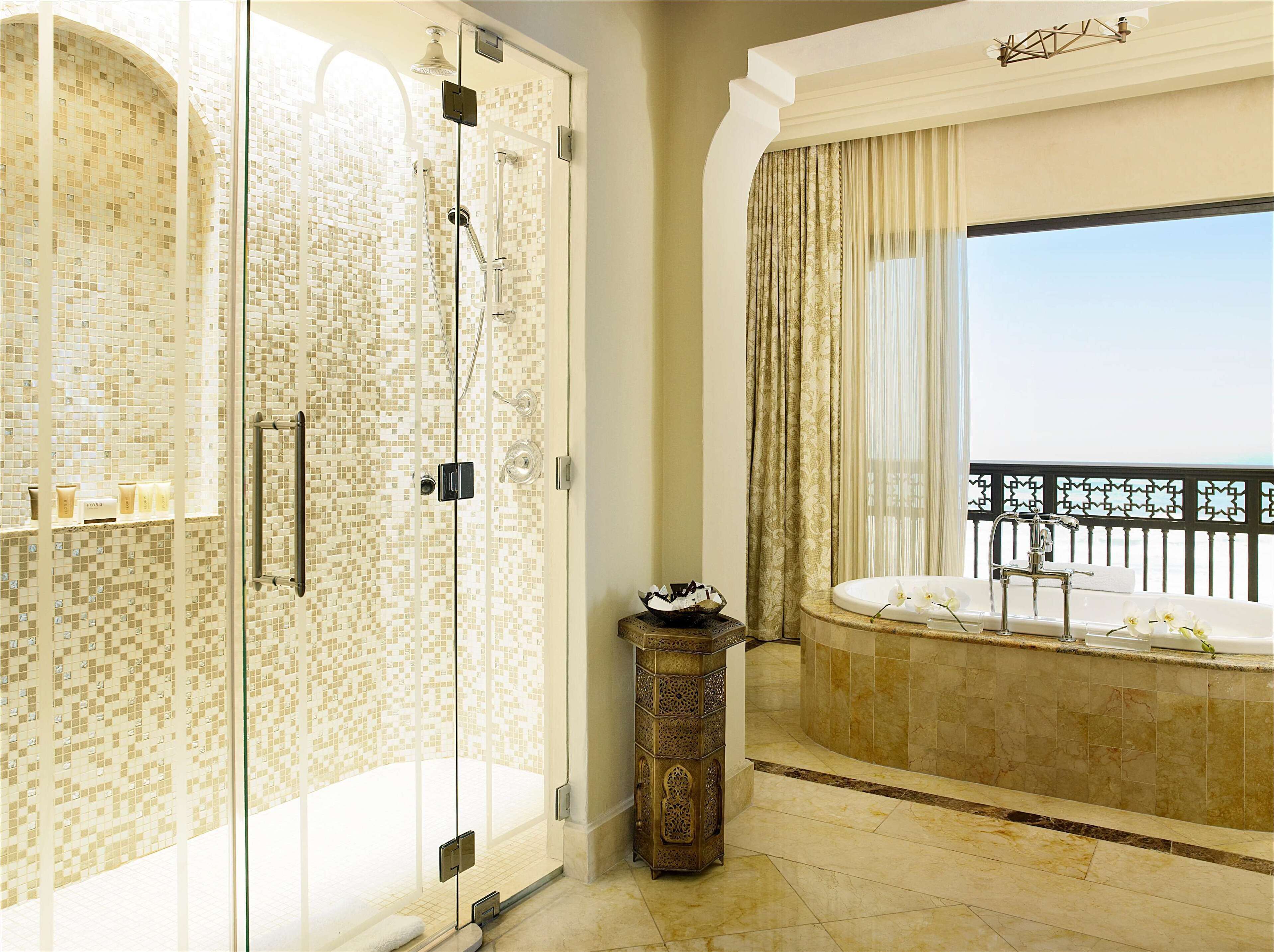 A luxurious bathroom with a glass-enclosed shower, a freestanding bathtub, and a balcony with a view.