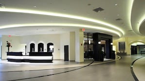 Un hall d’hôtel moderne doté d’un comptoir d’accueil, d’un plafond aux lignes courbes et d’une entrée en verre.