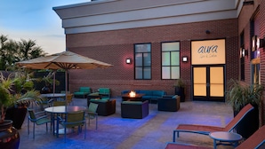 Un espace extérieur aménagé en terrasse, avec des sièges, un foyer et un panneau indiquant la présence d’un spa et d’un salon de beauté.