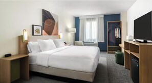 A hotel room with a large bed, bedside tables, a TV, a wardrobe, and a window with curtains. - Spark by Hilton Artesia (Artesia)