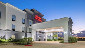 Un hotel Hampton Inn & Suites con una fachada moderna, ventanas amplias y una entrada bien iluminada.