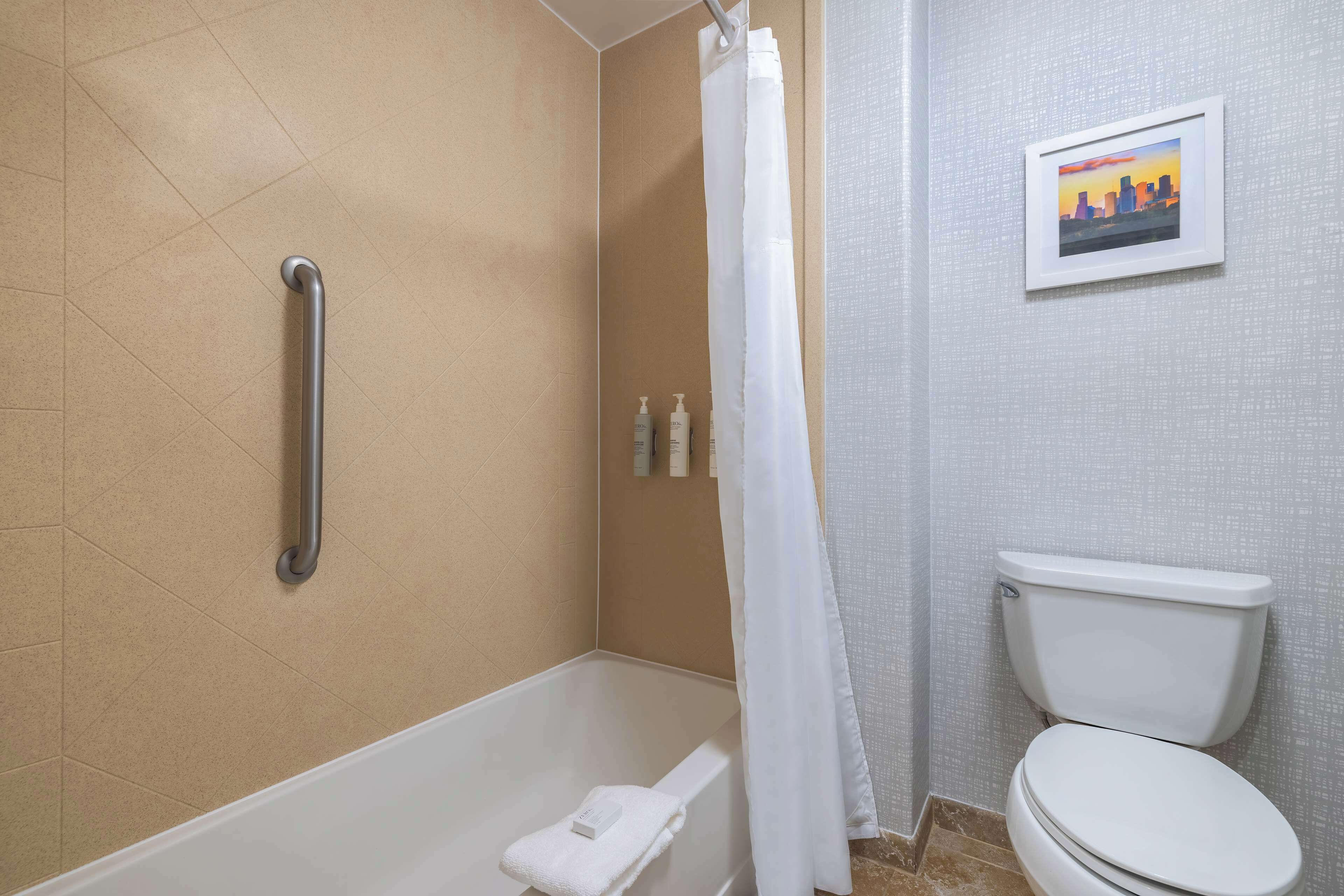 Ein Badezimmer mit Dusche, Toilette und Haltegriff.