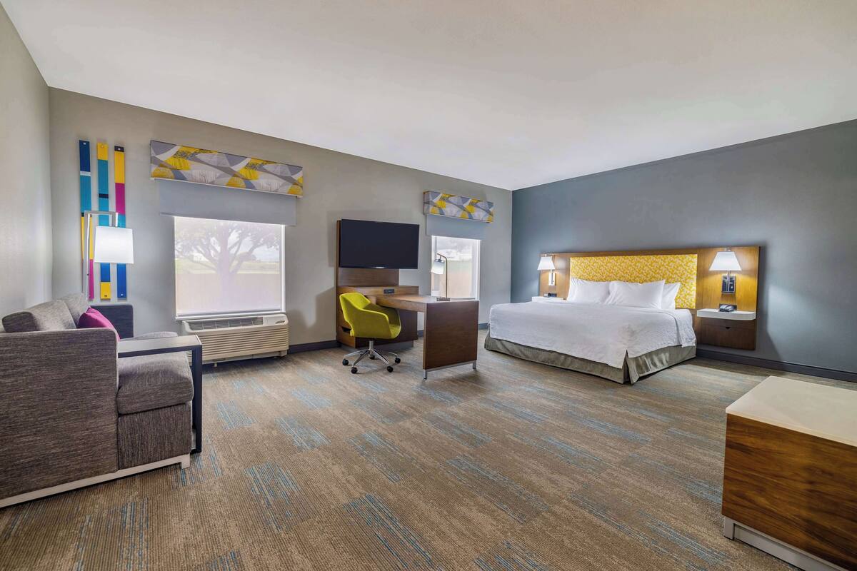 Une chambre d’hôtel avec un lit, un bureau, une chaise, une télévision et une fenêtre.