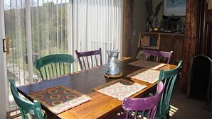 A dining area with a wooden table, colorful placemats, and chairs. - Mount Snow Condominiums (West Dover)