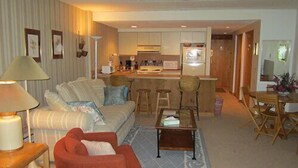 A living room with a sofa, armchair, coffee table, and a dining area with a table and chairs. - Mount Snow Condominiums (West Dover)