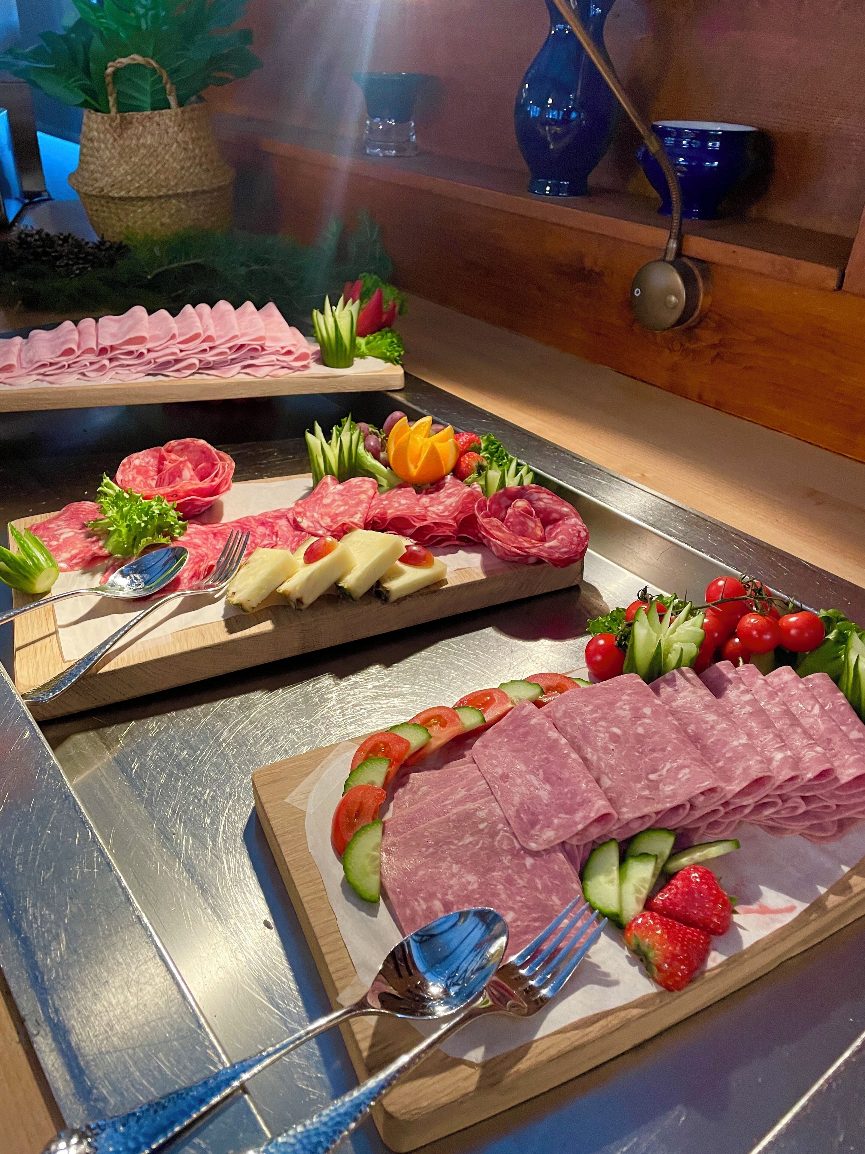A buffet with various meats, cheeses, and fruits.