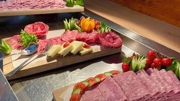 A buffet with various meats, cheeses, and fruits.