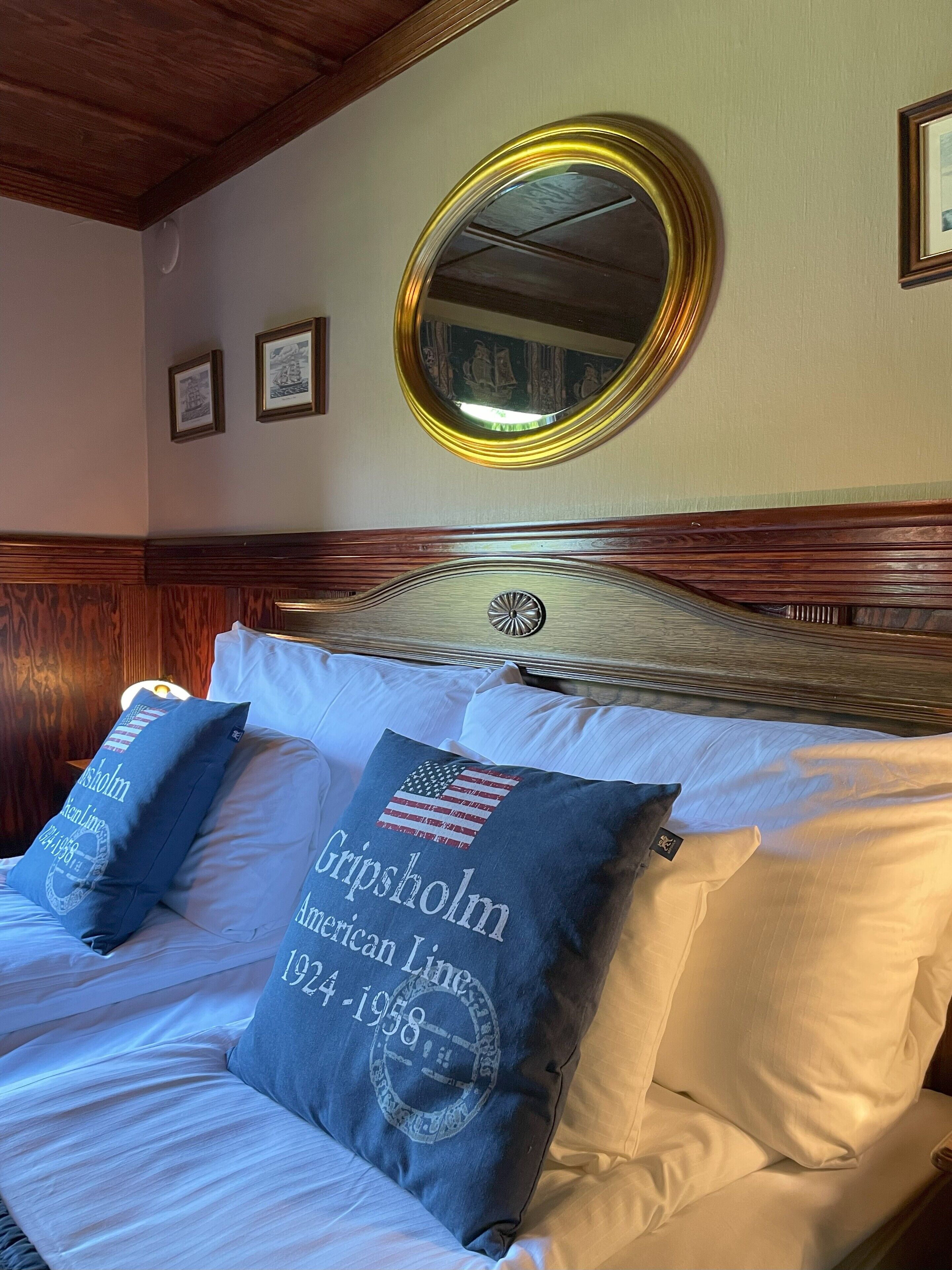 A neatly made bed with two pillows, one with a historical date and another with a flag.