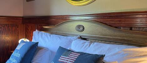 A neatly made bed with two pillows, one with a historical date and another with a flag.