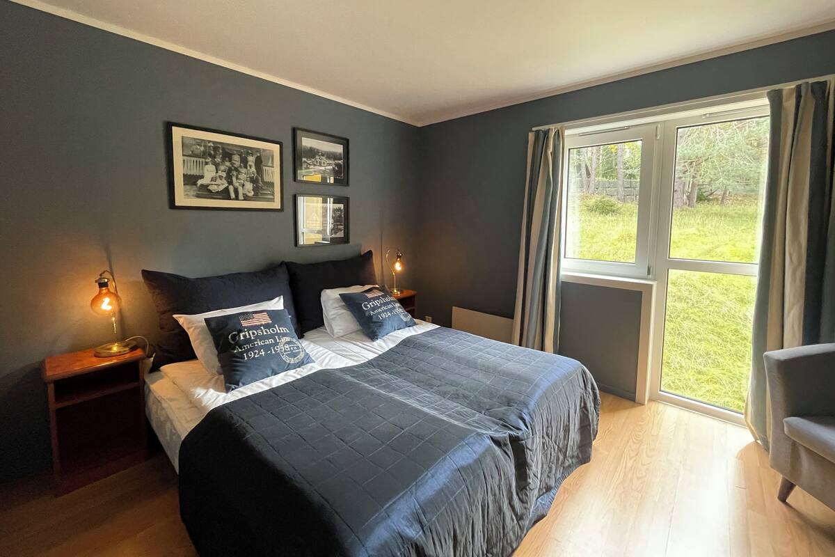 A bedroom with a large bed, two bedside lamps, and a window with curtains.