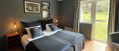 A bedroom with a large bed, two bedside lamps, and a window with curtains.