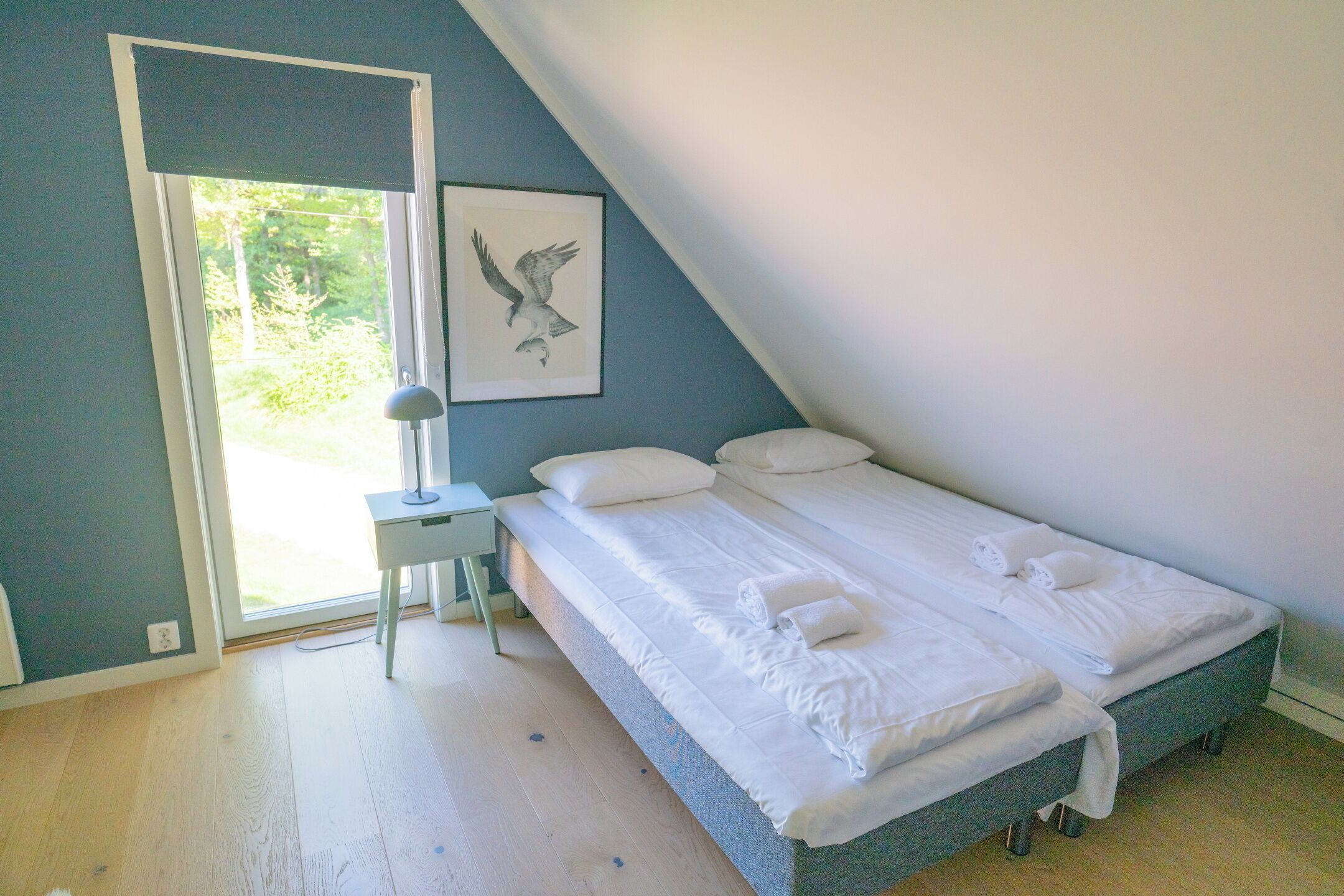 A bedroom with a bed, a bedside table, a lamp, and a framed picture on the wall.