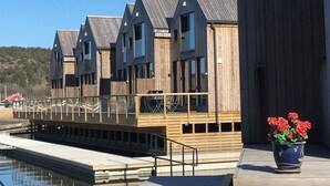 Una hilera de edificios de madera con balcones, un muelle y una masa de agua.