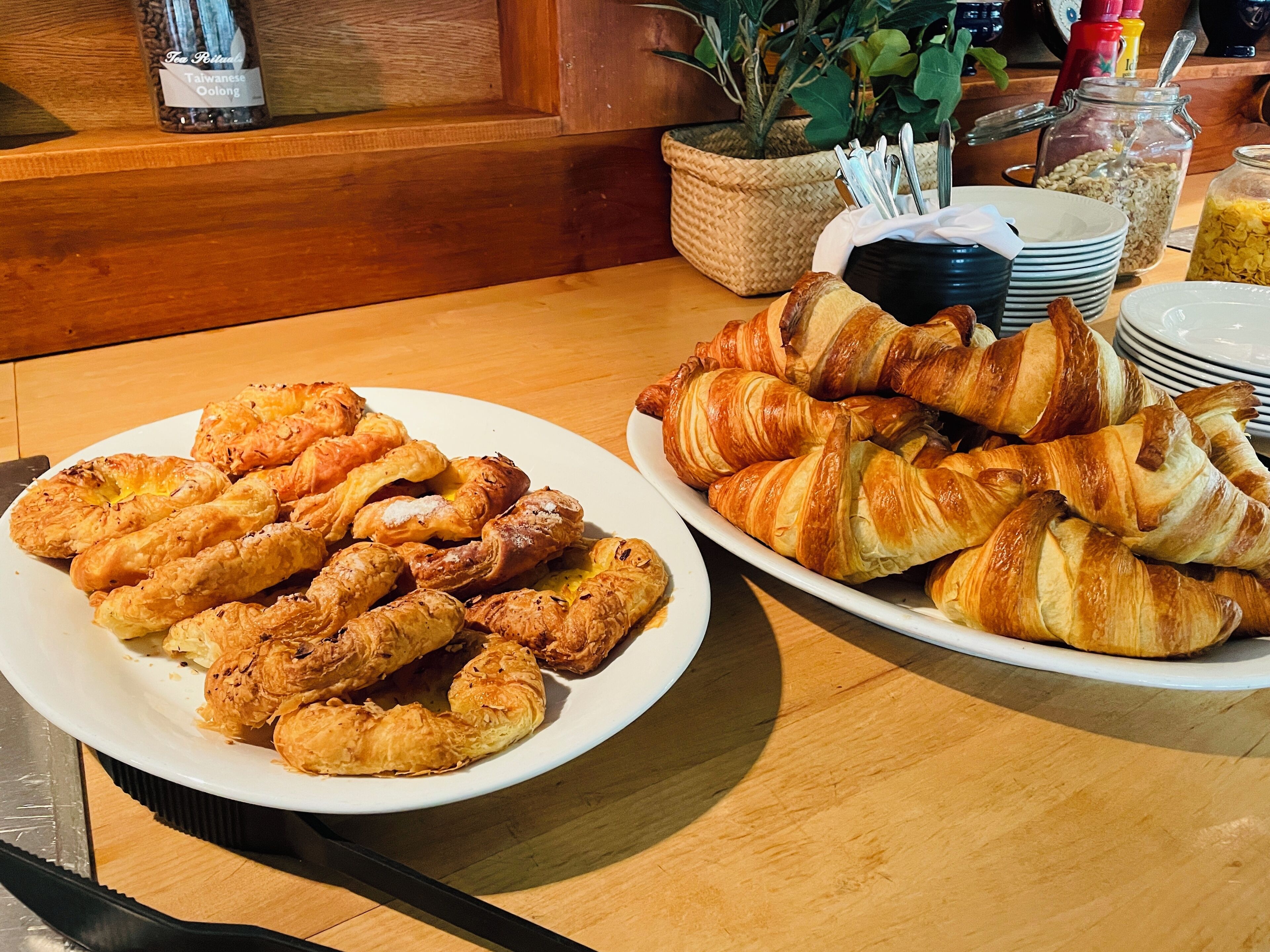 Een ontbijtbuffet met schalen vol gebak en diverse ontbijtartikelen.