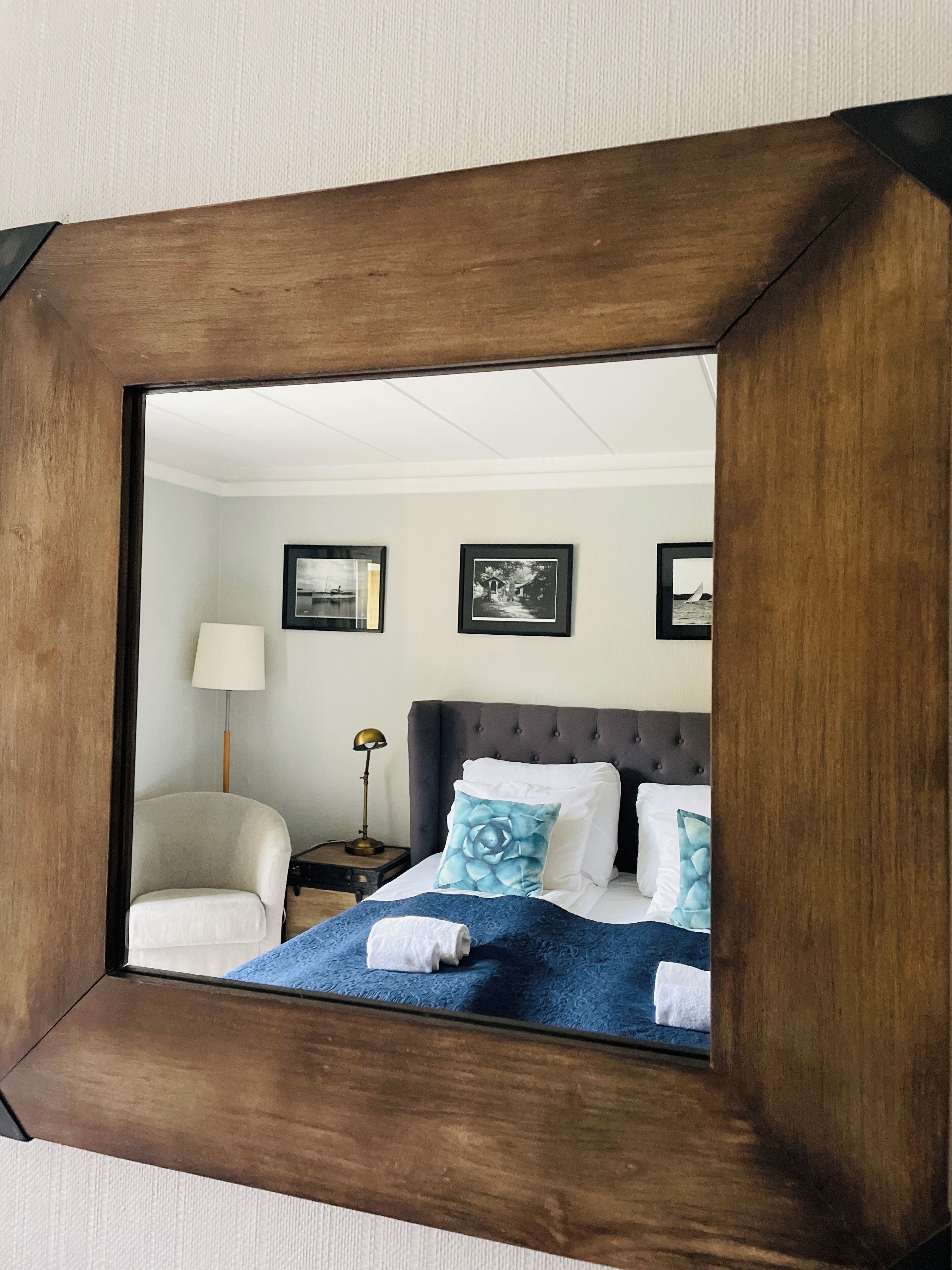 A bedroom with a bed, a chair, a nightstand, and framed pictures on the wall.