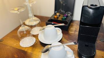 Une table avec une machine à café, deux tasses avec des cuillères et un verre avec une cuillère.