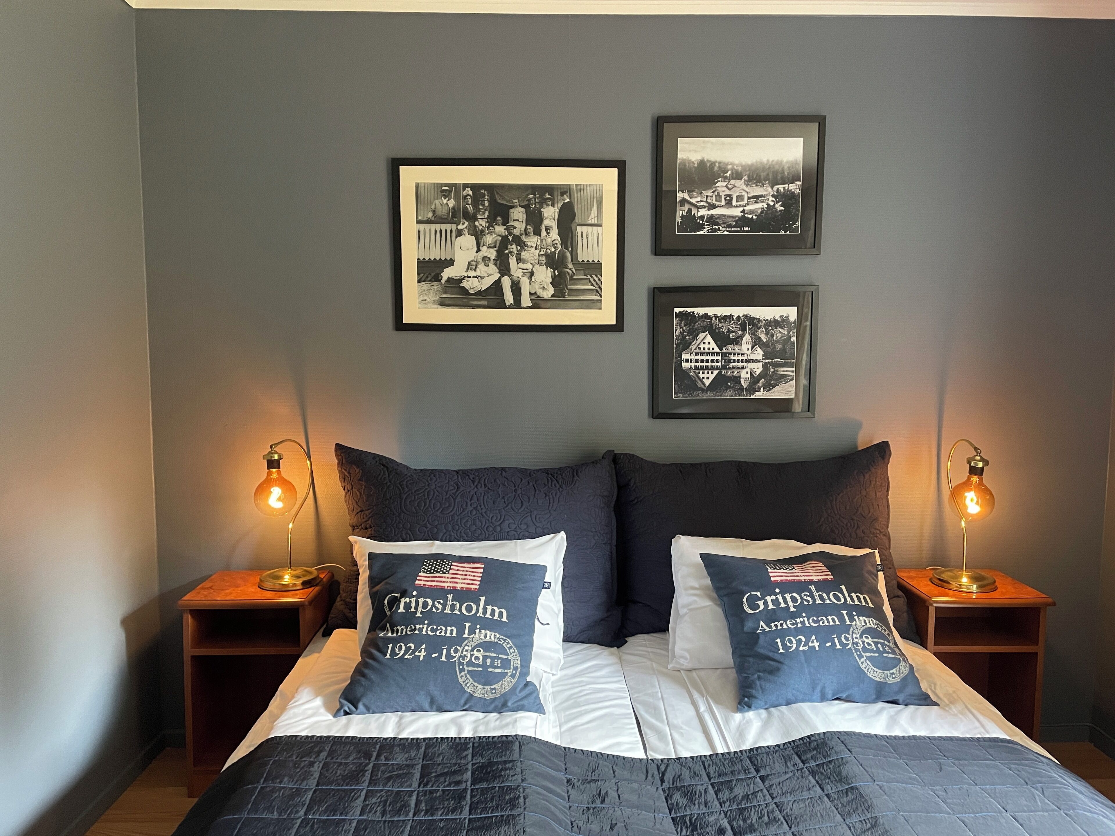 Un dormitorio con una cama, dos almohadas, dos mesitas de noche y dos lámparas de pared.