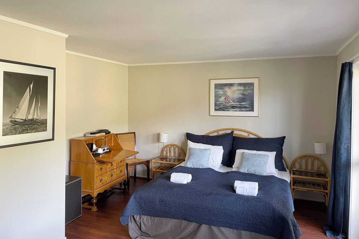 A neatly arranged bedroom with a bed, bedside tables, a dresser, and two chairs.