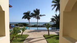 A pathway leading to a pool with palm trees and lounge chairs. - Barefoot Beach Pad (Cabarete)