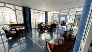 Una habitación amplia con ventanas grandes, una mesa de centro de vidrio y asientos cómodos.