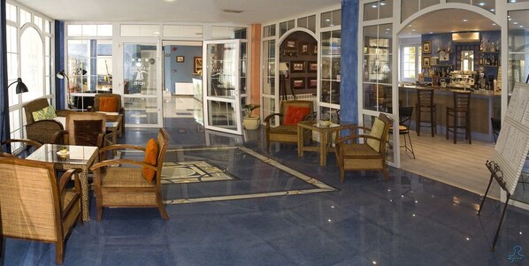 A spacious lobby with a bar area, seating arrangements, and a glass door entrance. - Hotel Arha Villa de Suances (Suances)