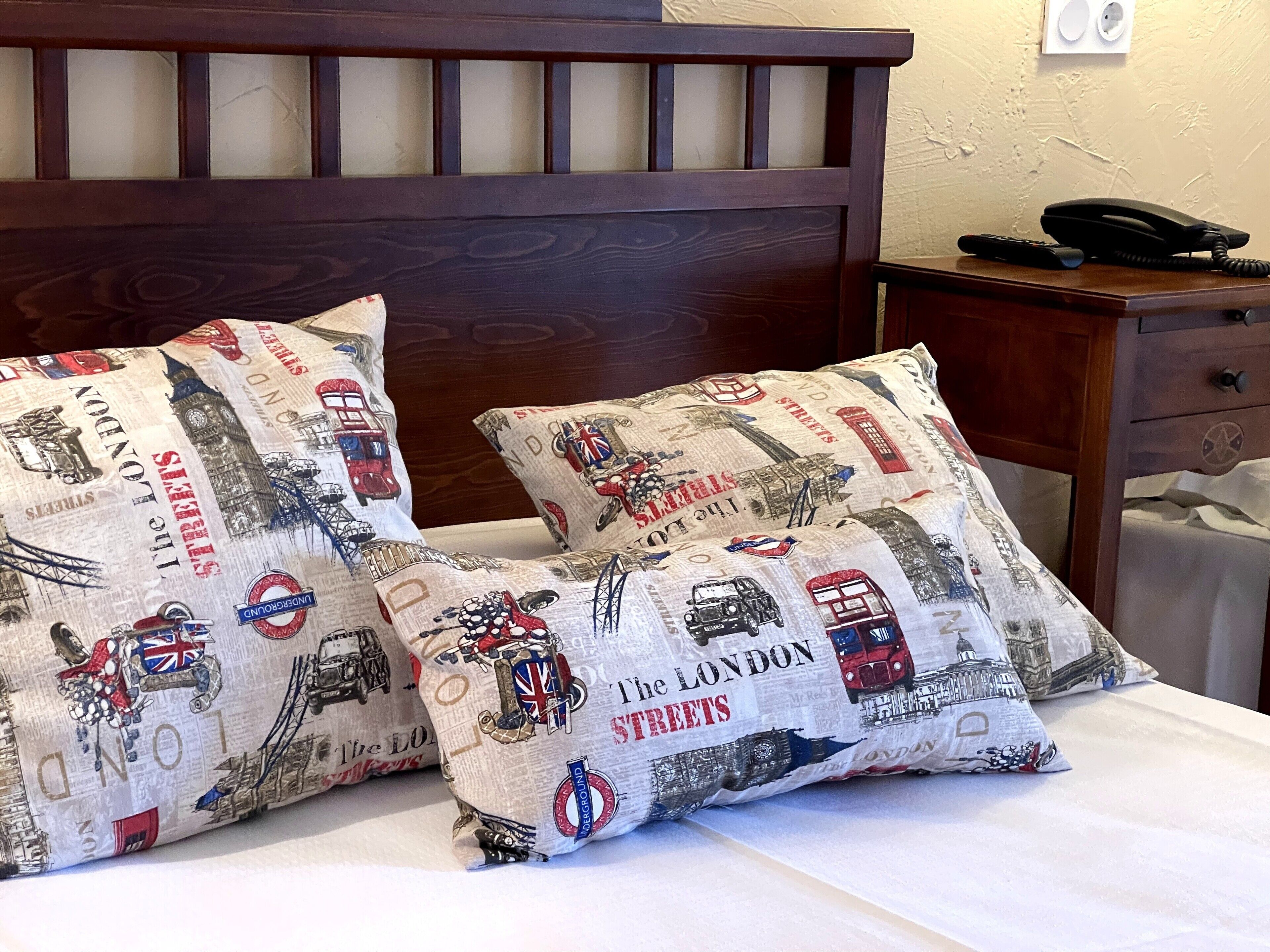 Una cama con dos almohadas que muestran escenas de las calles de Londres.