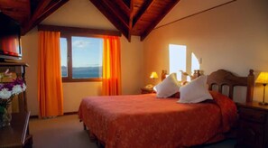 Une chambre d’hôtel avec un lit, une table de chevet, une lampe et une fenêtre avec des rideaux.