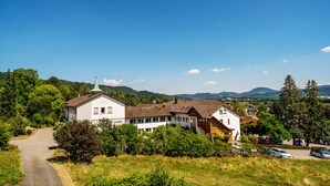 A white building with a green roof and a church steeple, surrounded by greenery and a clear blue sky. - St. Fridolin (Bad Saeckingen)