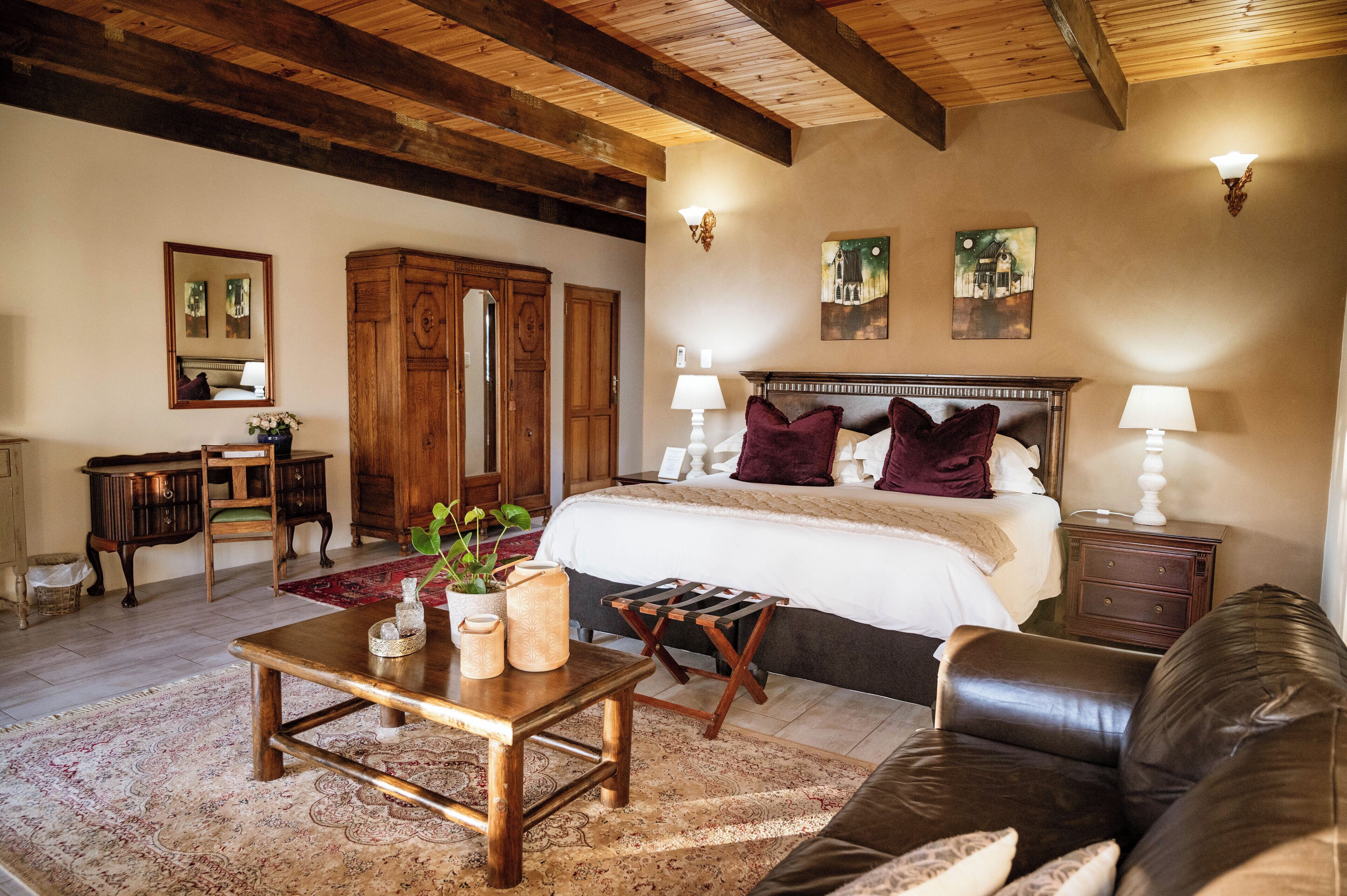 A cozy bedroom with a large bed, wooden furniture, and a rustic ceiling.