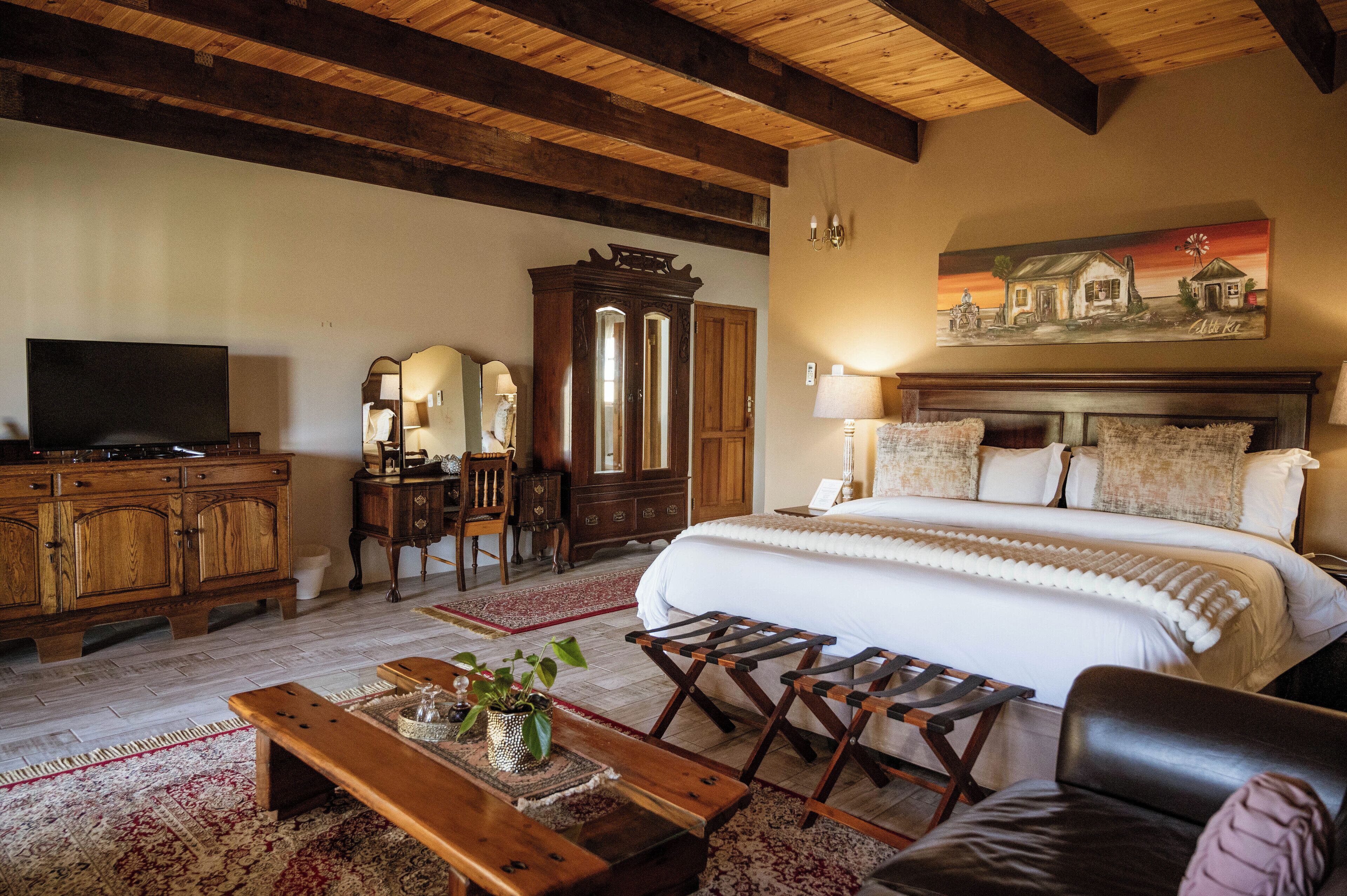 A bedroom with a large bed, wooden furniture, a television, and a painting on the wall.