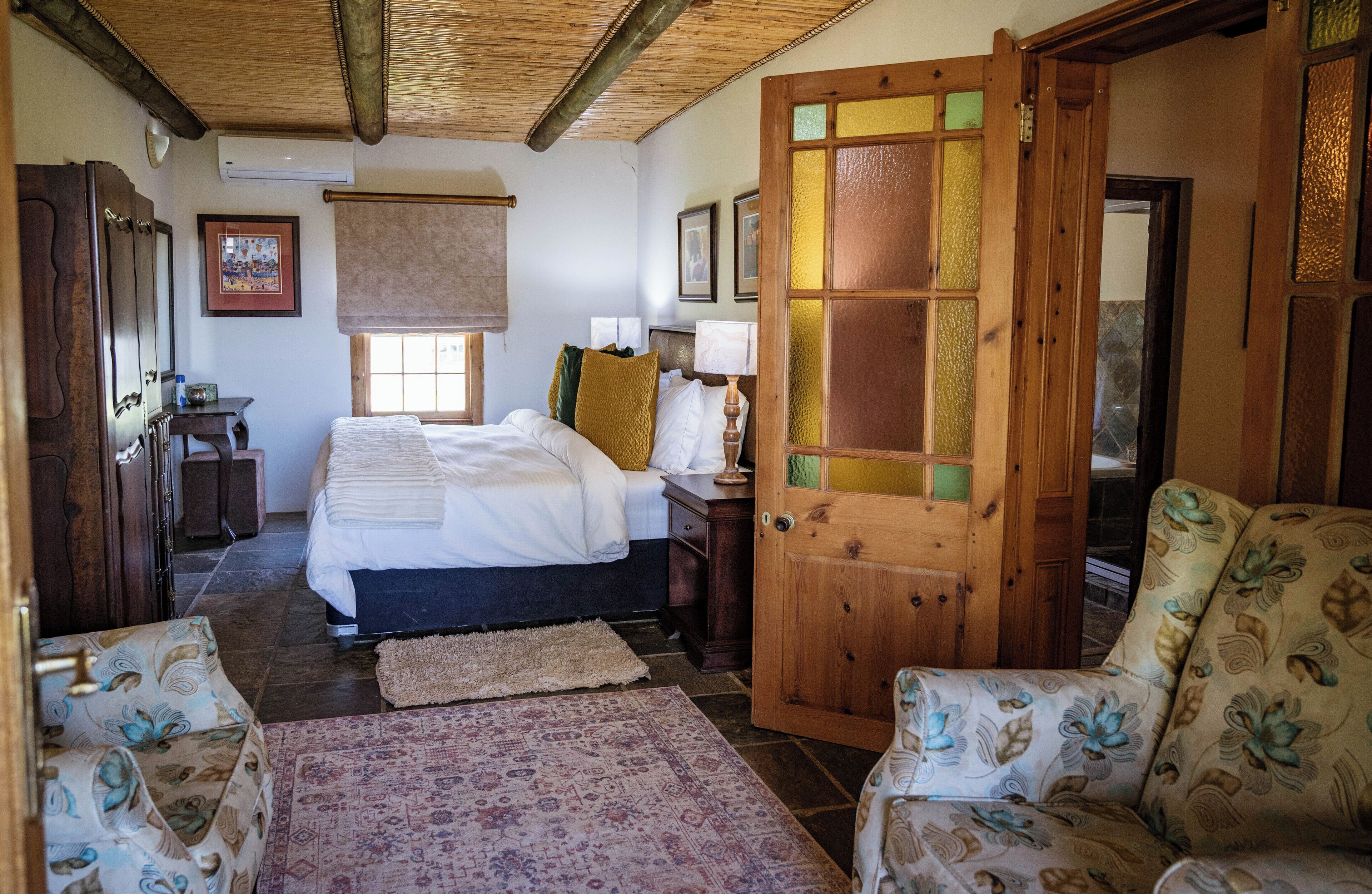 A bedroom with a bed, a wooden door, a desk, and a chair.