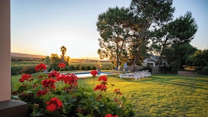 A pool area with lounge chairs, surrounded by a well-maintained lawn and flowering plants.